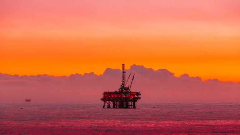 The image displays an oil drilling platform in a body of water