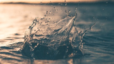 photo depicts a drop of water hitting the surface of a large body of water